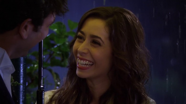 Josh Radnor and Cristin Milioti as Ted and Tracy smiling at each other under an umbrella in How I Met Your Mother