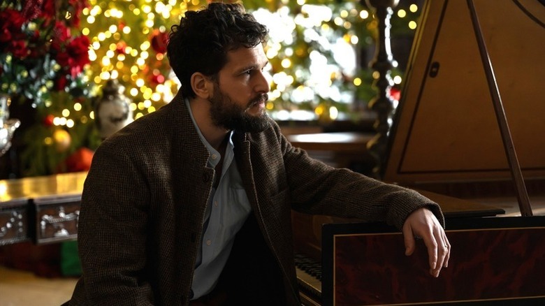 Henry Muck (Kit Harington) sits at a piano in Industry