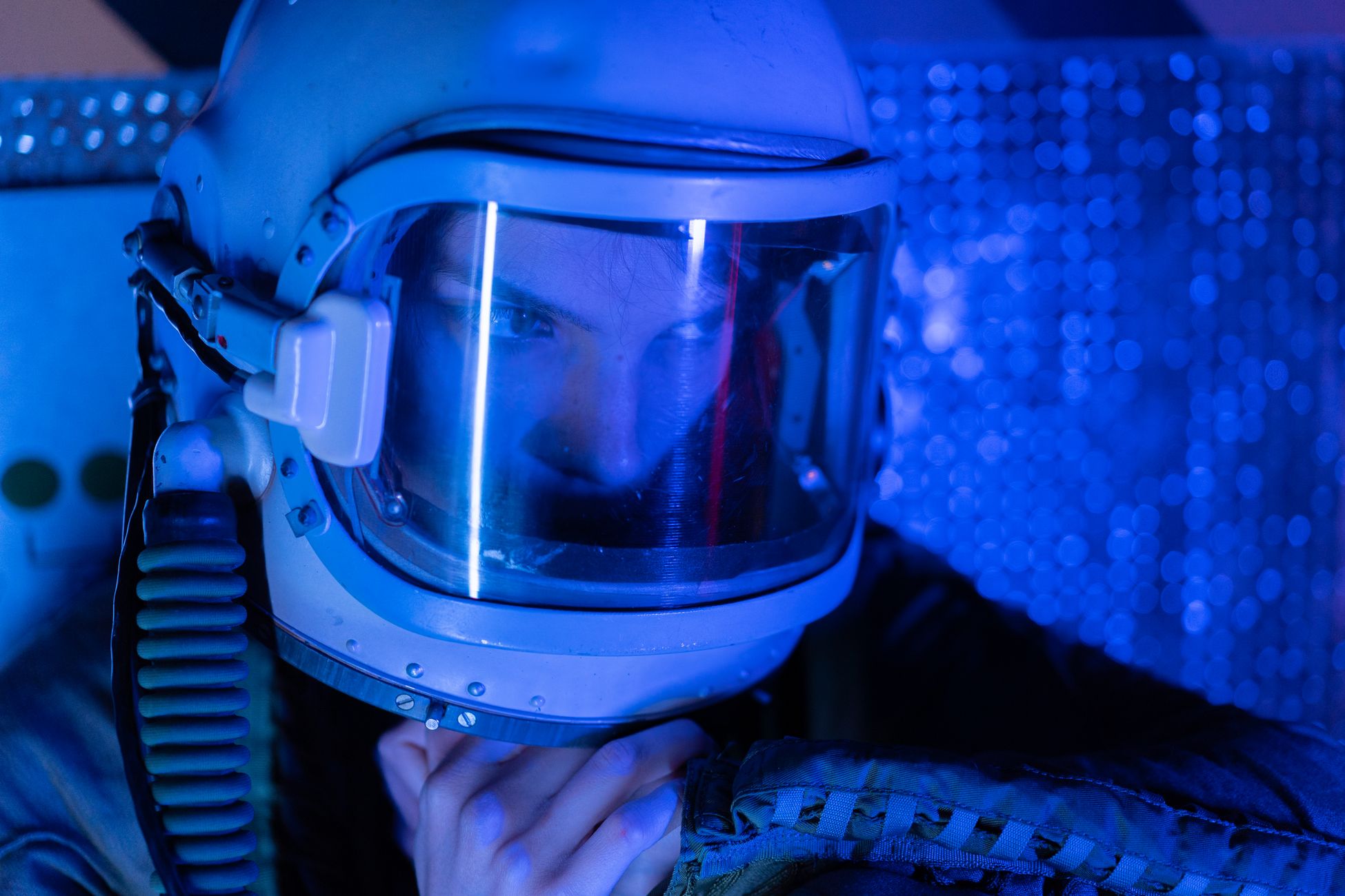An astronaut in a helmet with reflective visor explores a blue-lit space environment.