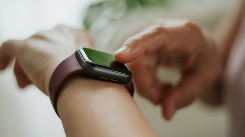 A person tapping the smartwatch on their wrist