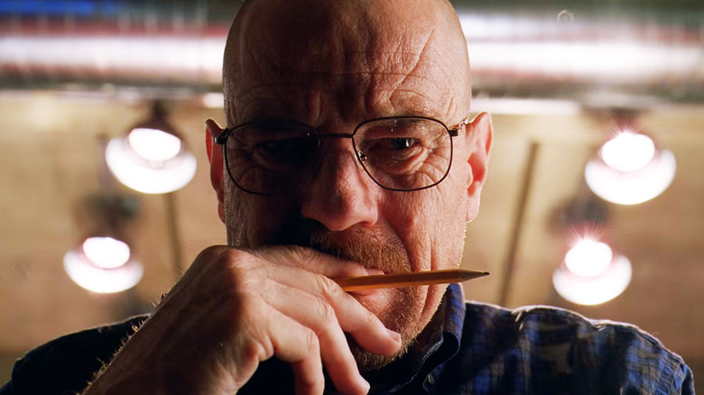 Bryan Cranston's Walter White looks down into camera while holding a pencil to his mouth in Breaking Bad
