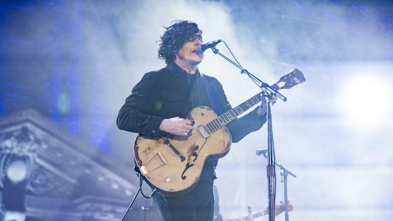Jack White onstage with microphone and acoustic guitar