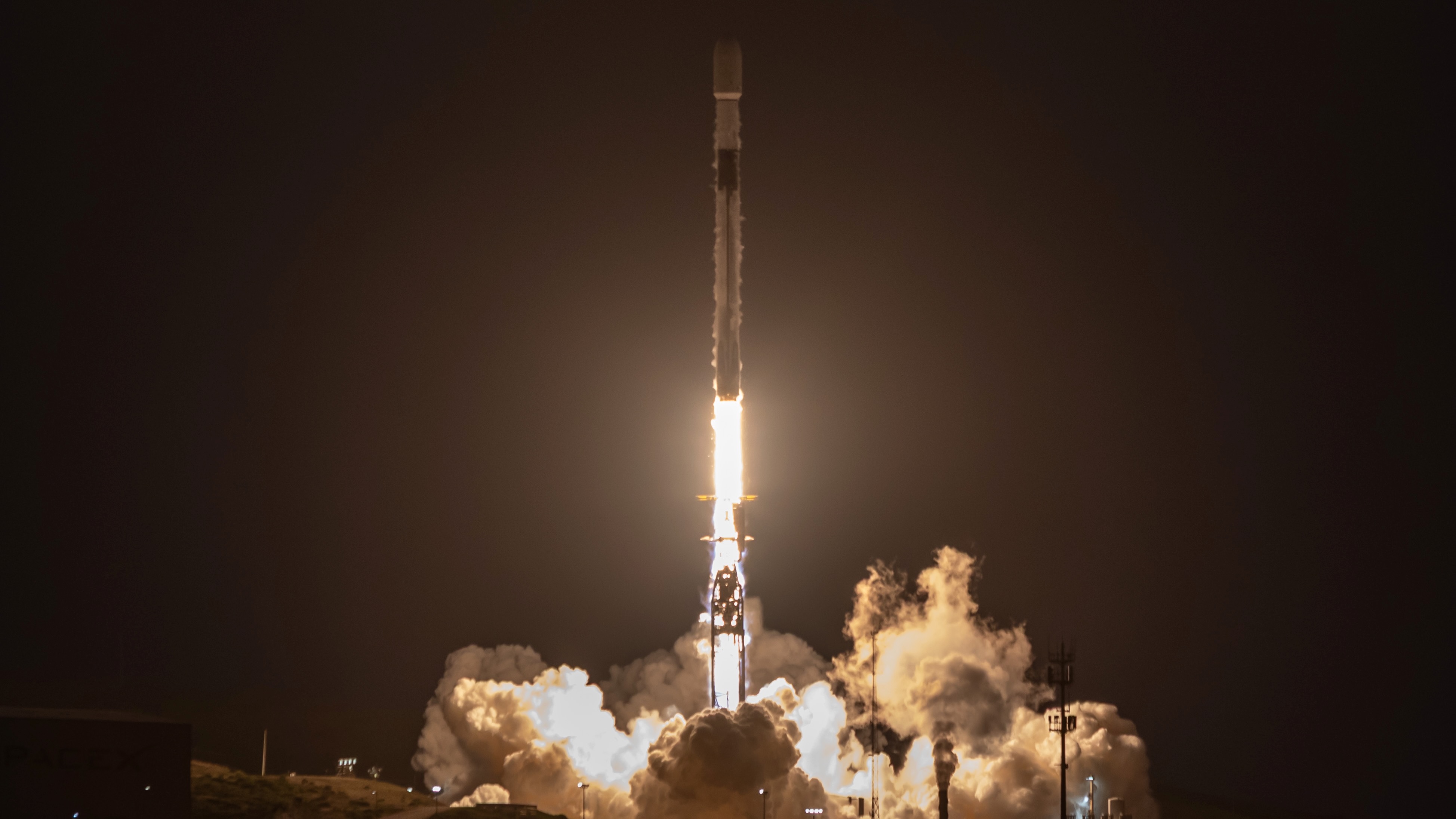 a black and white rocket launches into a dark night sky