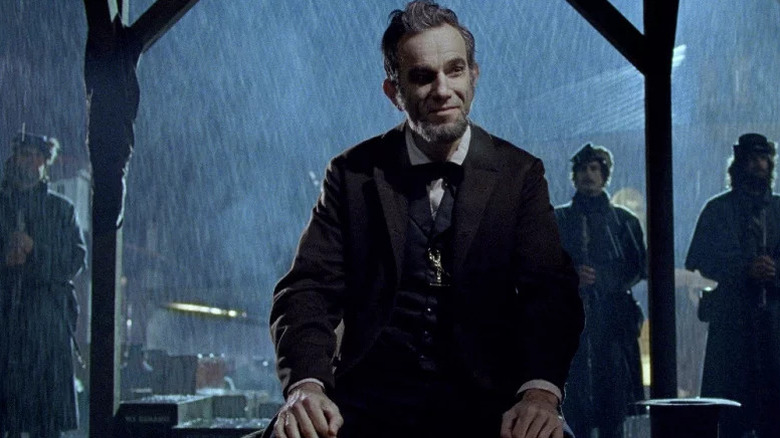 Abraham Lincoln (Daniel Day-Lewis) sits smiling in the rain in Lincoln