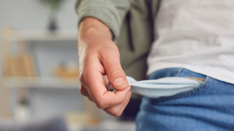 A man pulling out the insides of his pocket to show that it's empty