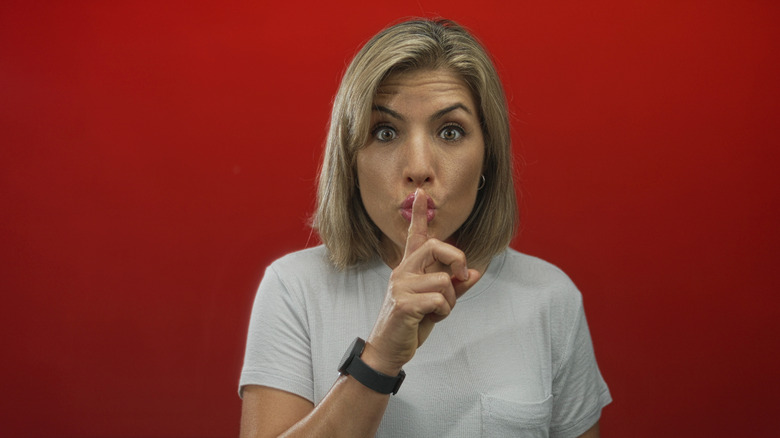 a woman with a smartwatch hushing the camera