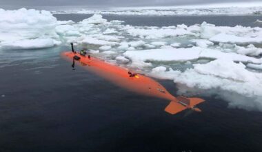 Bright orange autonomous submarine Ran floating among Antarctic sea ice during a mission near the Dotson Ice Shelf.