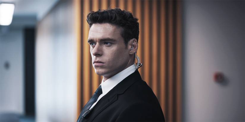 Richard Madden in Bodyguard standing in a suit with an earpiece.