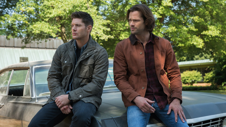 Dean and Sam sit on hood of car