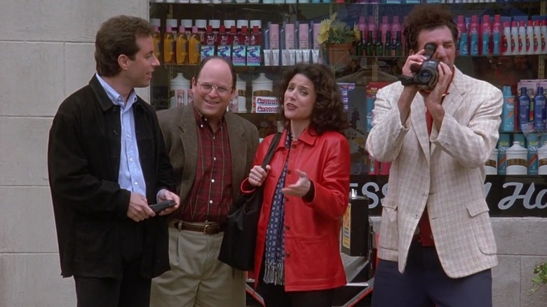 Jerry Seinfeld as Jerry, Jason Alexander as George, Julia Louis-Dreyfus as Elaine, and Michael Richards as Kramer with a camera standing on the street in Seinfeld