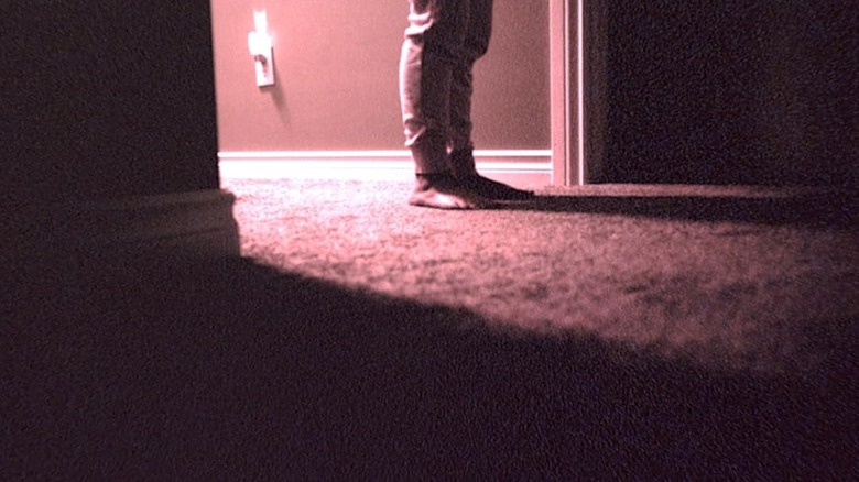 A pair of feet standing in a door in Skinamarink