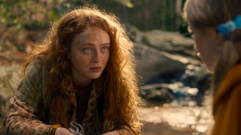 Sadie Sink as Max talking to Nell Fisher as Holly in a forest in Stranger Things 5