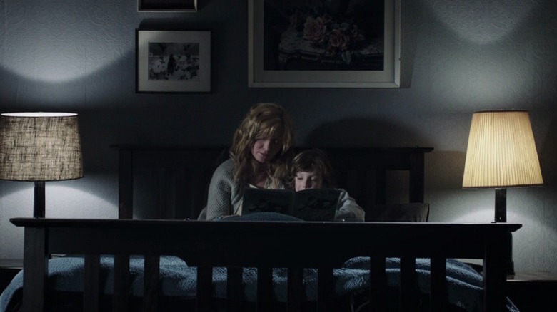 Essie Davis as Amelia Vanek and Noah Wiseman as Samuel Vanek in The Babadook, sitting in bed together as Amelia reads Samuel a book.