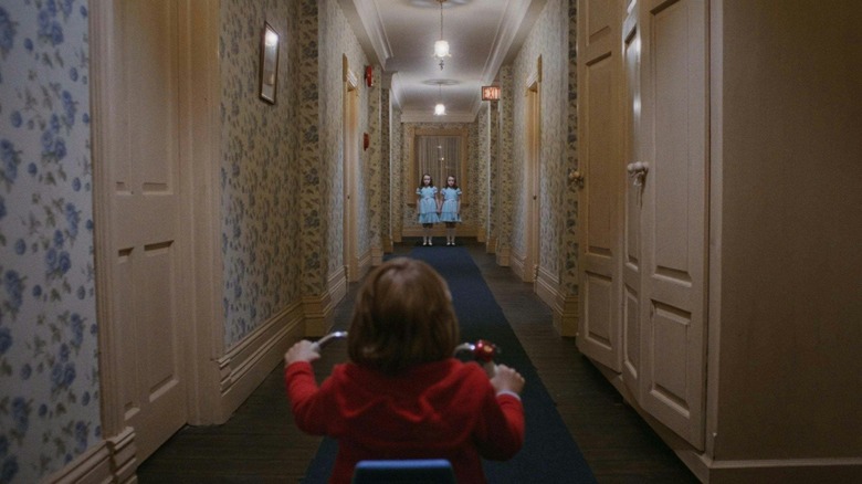 Danny looking at two young girls at the end of a hallway in The Shining