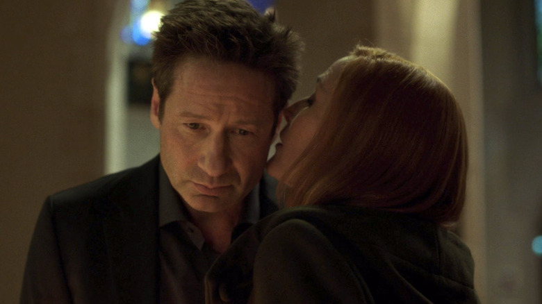 Gillian Anderson as Scully whispering in David Duchovny as Mulder's ear in The X-Files season 11