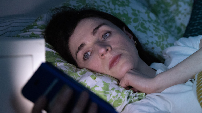 Áine checking her phone in bed