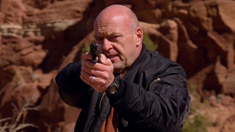 Dean Norris as Hank aiming a gun in the desert in Breaking Bad