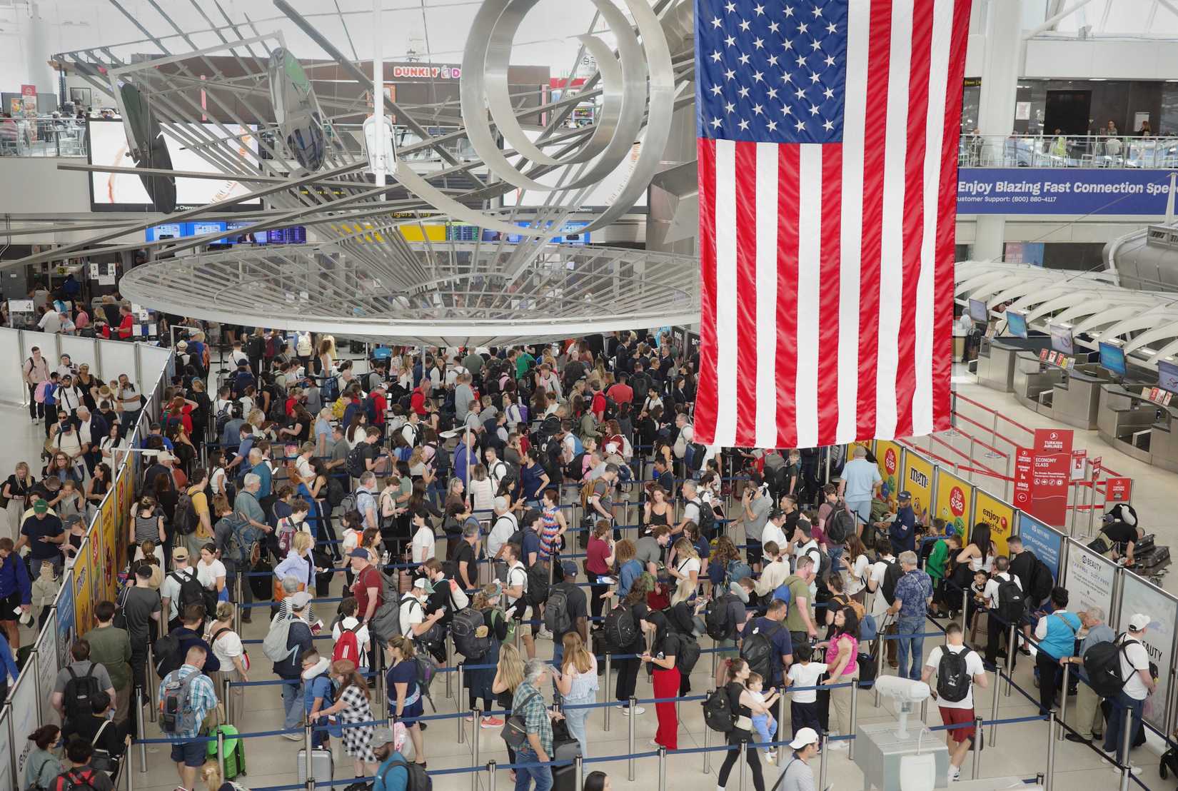 Travelers jam a security check point at JFK Airport on the eve of the July 4th holiday.
