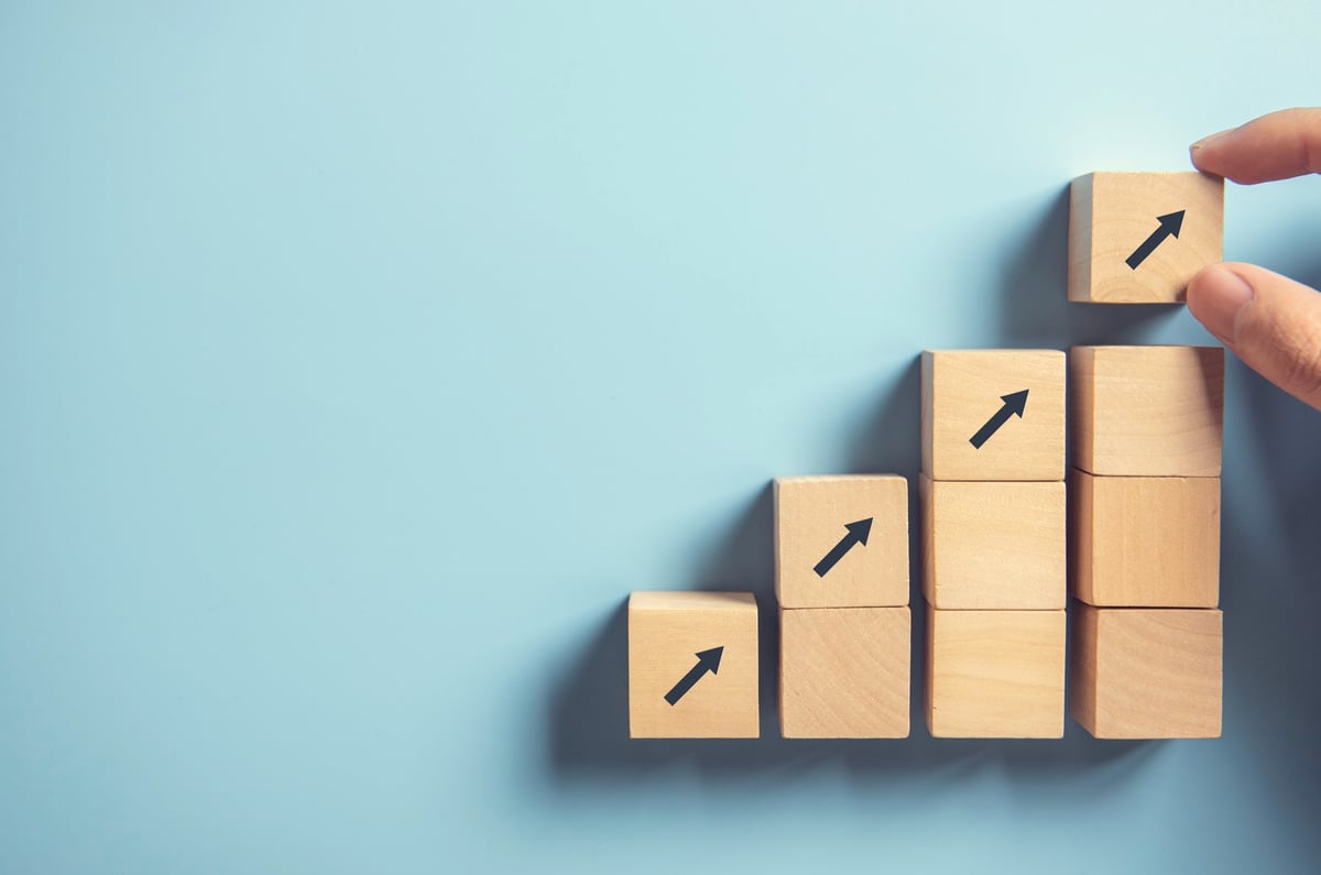An ascending stack of wooden blocks with arrows pointing up.