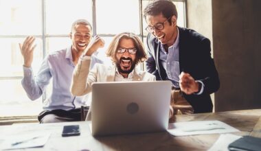 Three people looking at laptop and celebrating.