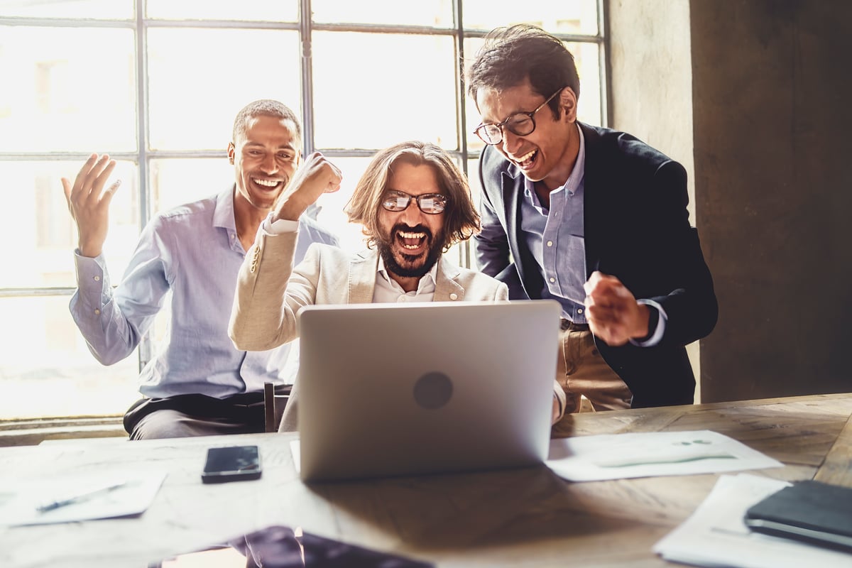 Three people looking at laptop and celebrating.