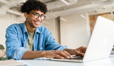 An investor smiles while working on a laptop.