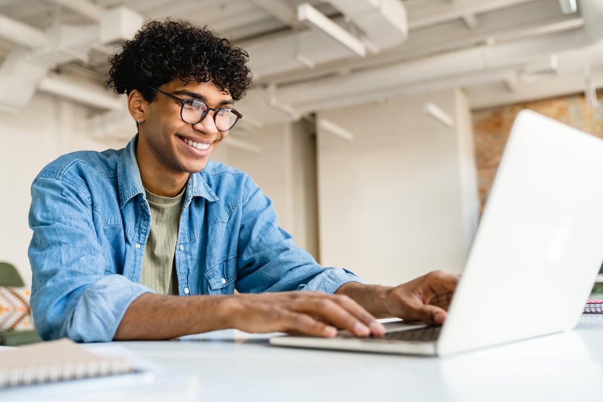 An investor smiles while working on a laptop.