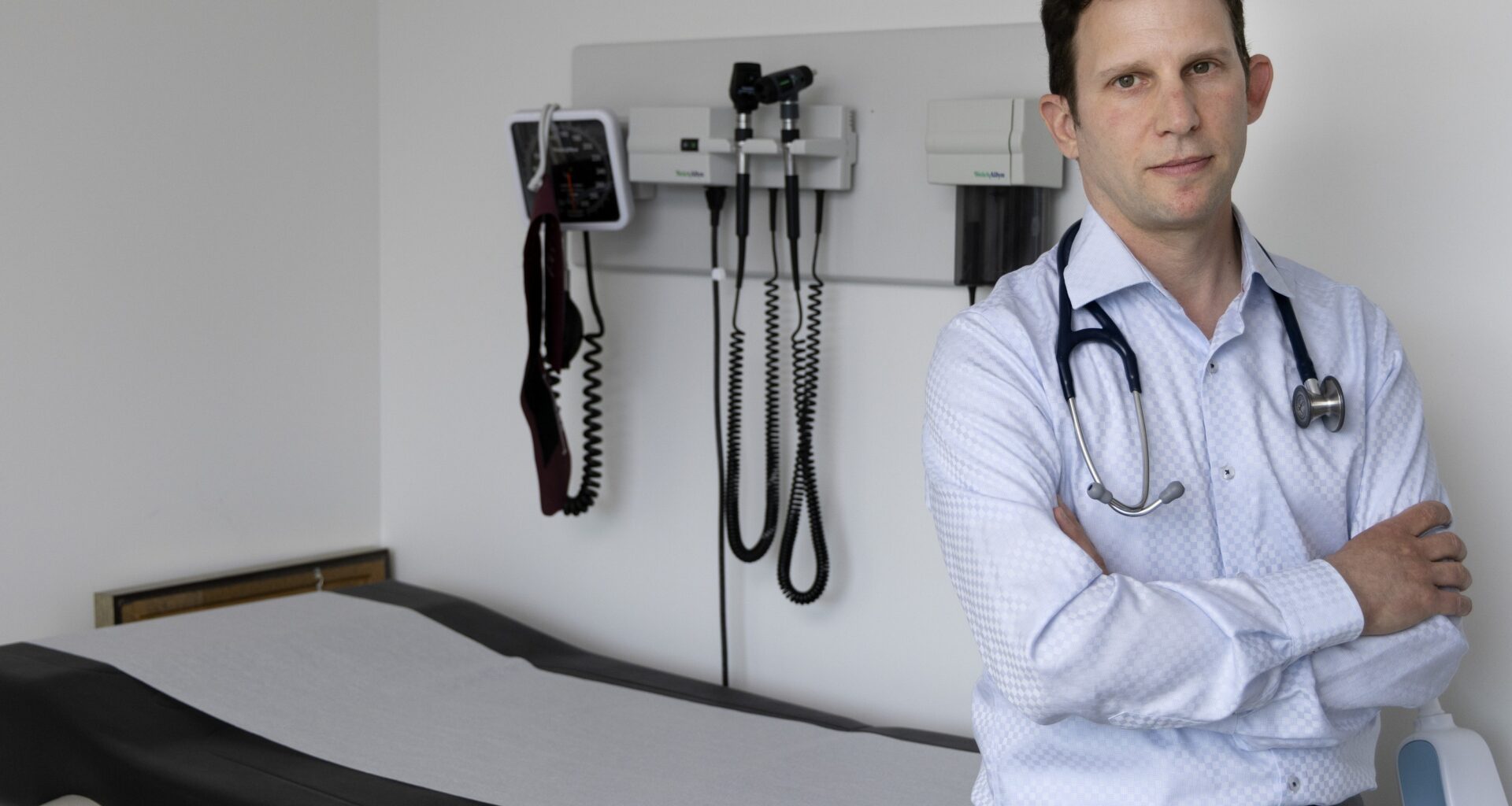 Dr. Michael Kalin poses for a photo next to a clinic patient bed.