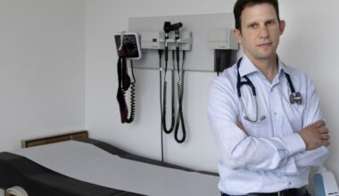 Dr. Michael Kalin poses for a photo next to a clinic patient bed.