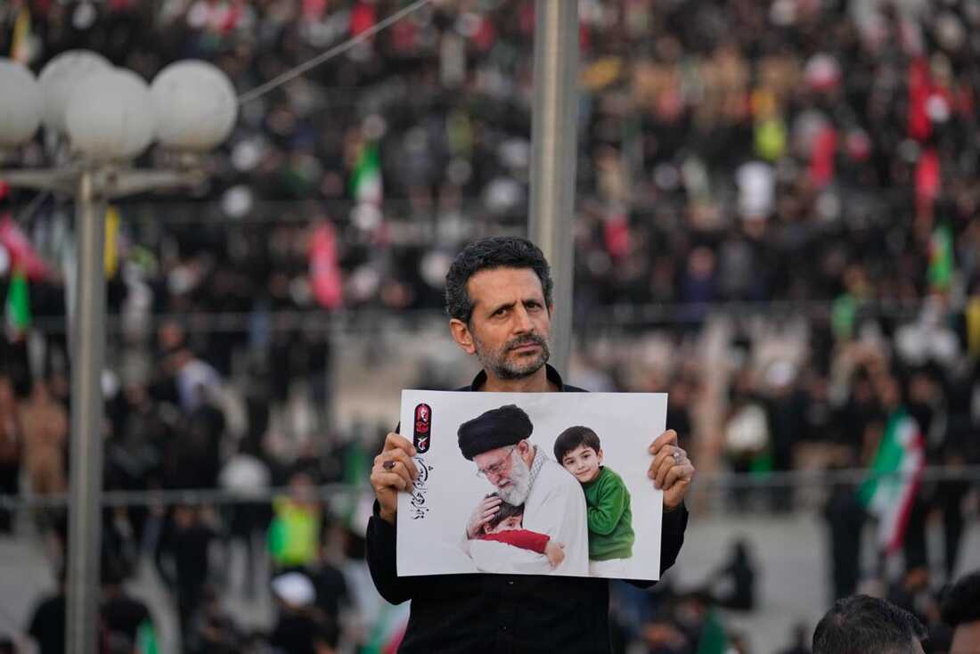 A man holds a picture of slain Iranian Supreme Leader Ayatollah Ali Khamenei as a crowd waits for his casket to arrive at the Imam Khomeini Mosalla Grand Mosque for the start of the dayslong funeral ceremonies in Tehran, Iran, Saturday, July 4, 2026.