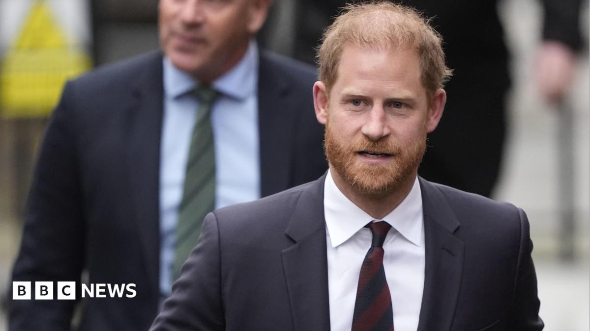 Prince Harry wearing a dark suit with a maroon tie.