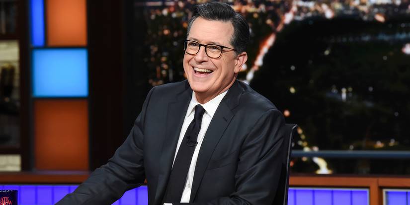 Stephen Colbert smiling behind his desk on 'The Late Show with Stephen Colbert.'