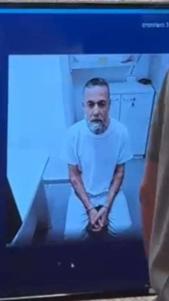 A man is seen sitting down on a video call cast on a monitor.
