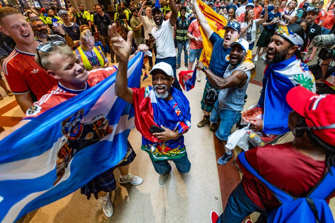 Scottish and Haitian fans dance and chant together inside Boston's South Station while waiting to board MBTA trains to the World Cup match between Scotland and Haiti in Foxborough, Mass., on Saturday, June 13.