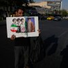 A man displays a placard with portraits of the current and late supreme leaders and the late Revolutionary Guard Gen. Qassem Soleimani at the Islamic Revolution Square in downtown Tehran, Iran, Saturday, July 18, 2026.