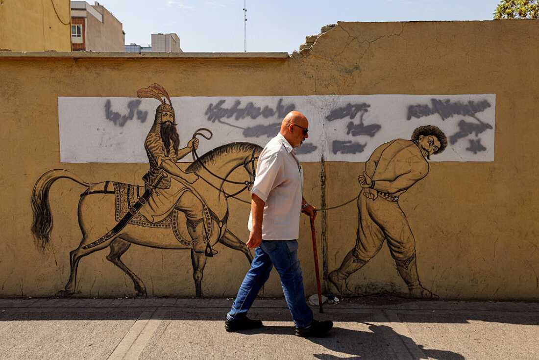 A man walks past a mural showing a refrence to an Iranian epic in Tehran on July 19, 2026.