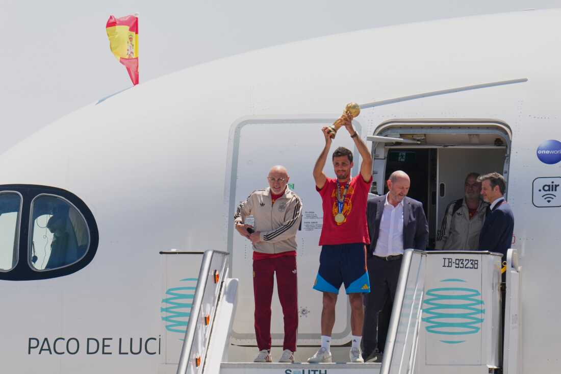 Spain's Rodrigo Hernandez lifts the World Cup trophy alongside Spain head coach Luis de la Fuente, left, and Royal Spanish Football Federation President Rafael Louzan as they arrive at Madrid airport on Monday, July 20, 2026, after Spain defeated Argentina in the World Cup final.