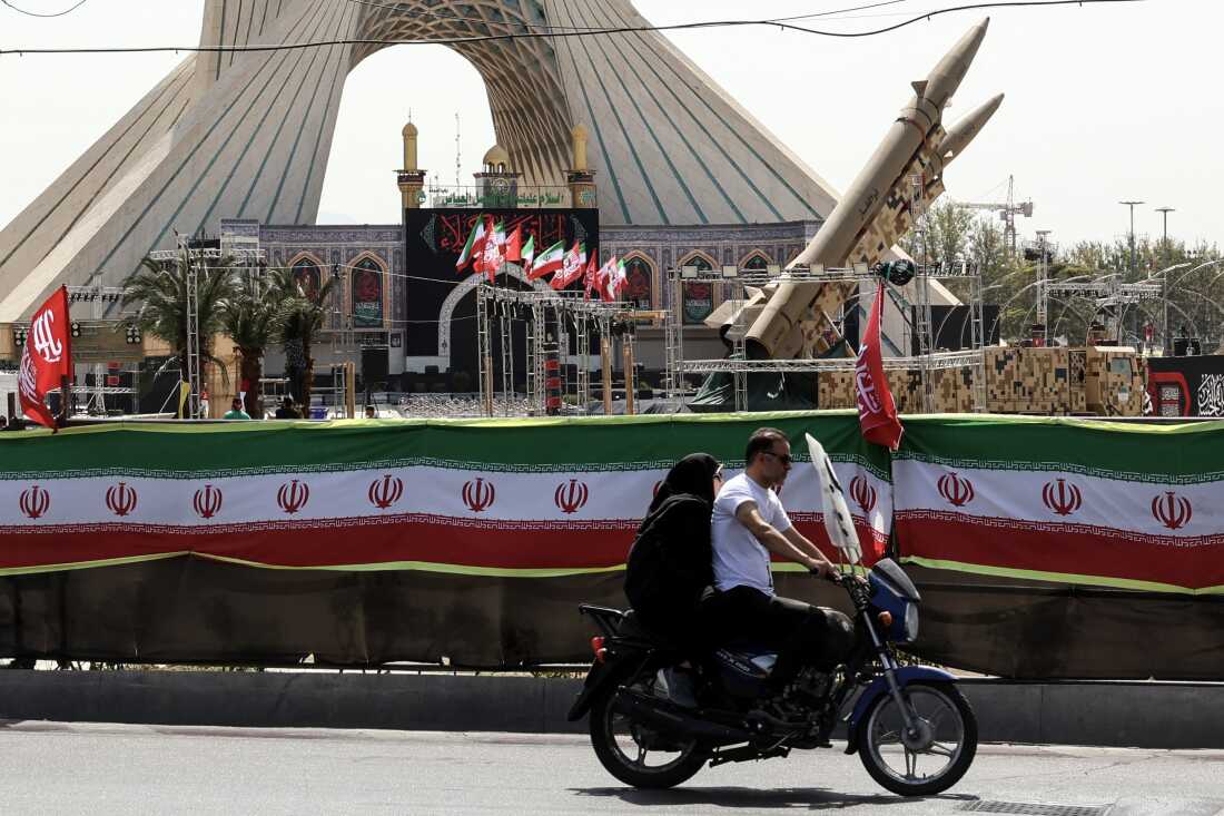 An Iranian couple rides past Iranian-made Zolfaghar missiles displayed at Azadi Square in Tehran on July 24, 2026. Iran's army said on July 24 it carried out drone strikes against several American military facilities and bases in Bahrain and Jordan in retaliation for the latest US attacks against the Islamic republic.