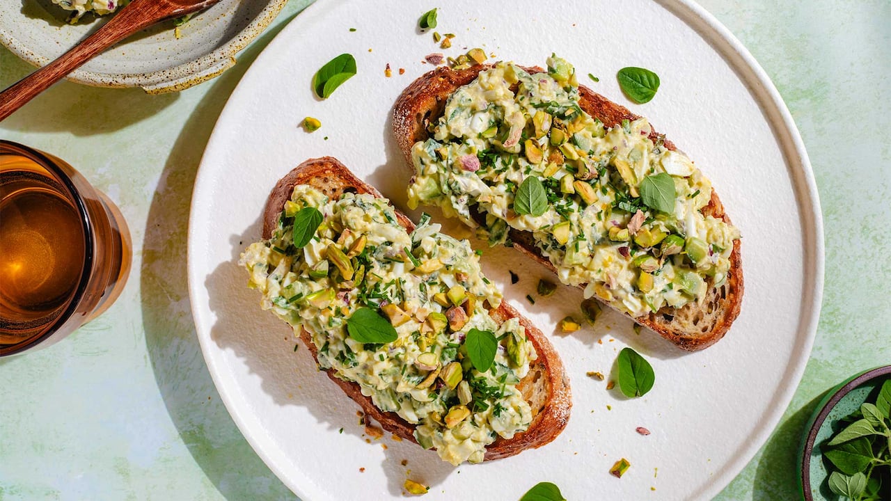 Overhead shot of 2 slices of sourdough on a plate with egg salad on them. 