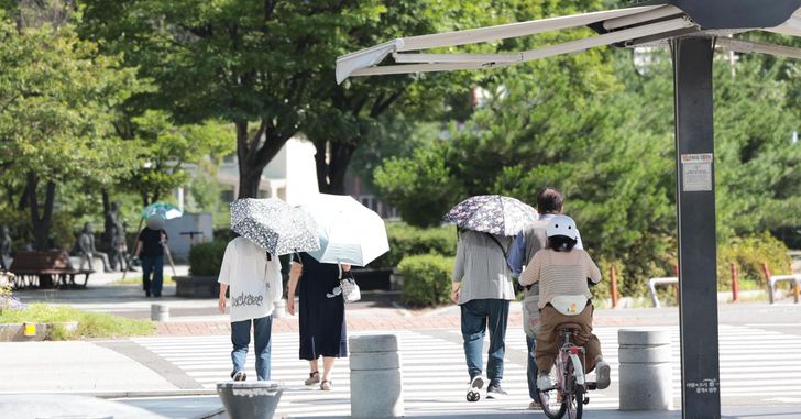 People carrying parasols walk along a street in Wansan District, Jeonju, North Jeolla Province, on Tuesday, when a heat wave advisory was in effect. Yonhap