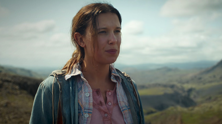 Millie Bobby Brown's Eleven stands in a natural landscape looking off into the distance in Stranger Things