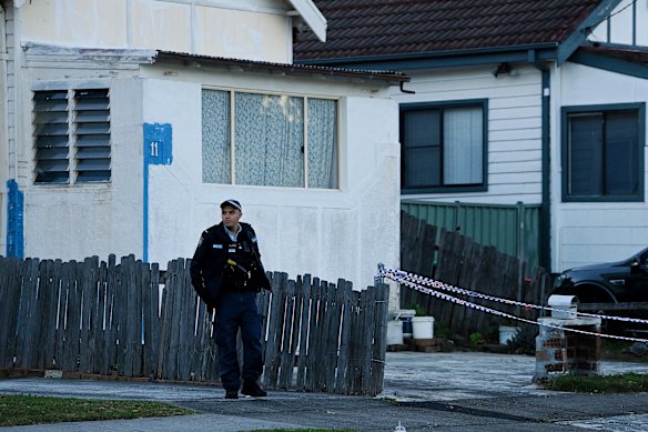A police officer watches on as detectives sweep through the Wiley Park granny flat on Thursday.