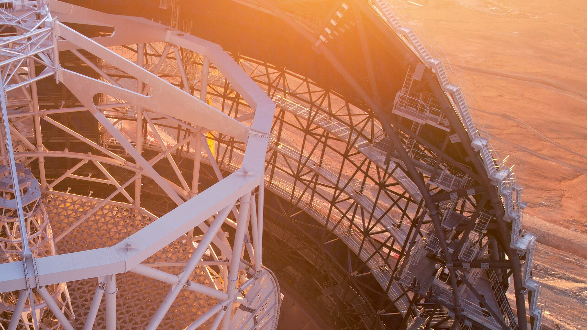 a long, steep stretch of white metal stairs lines the edge of a half-finished dome structure