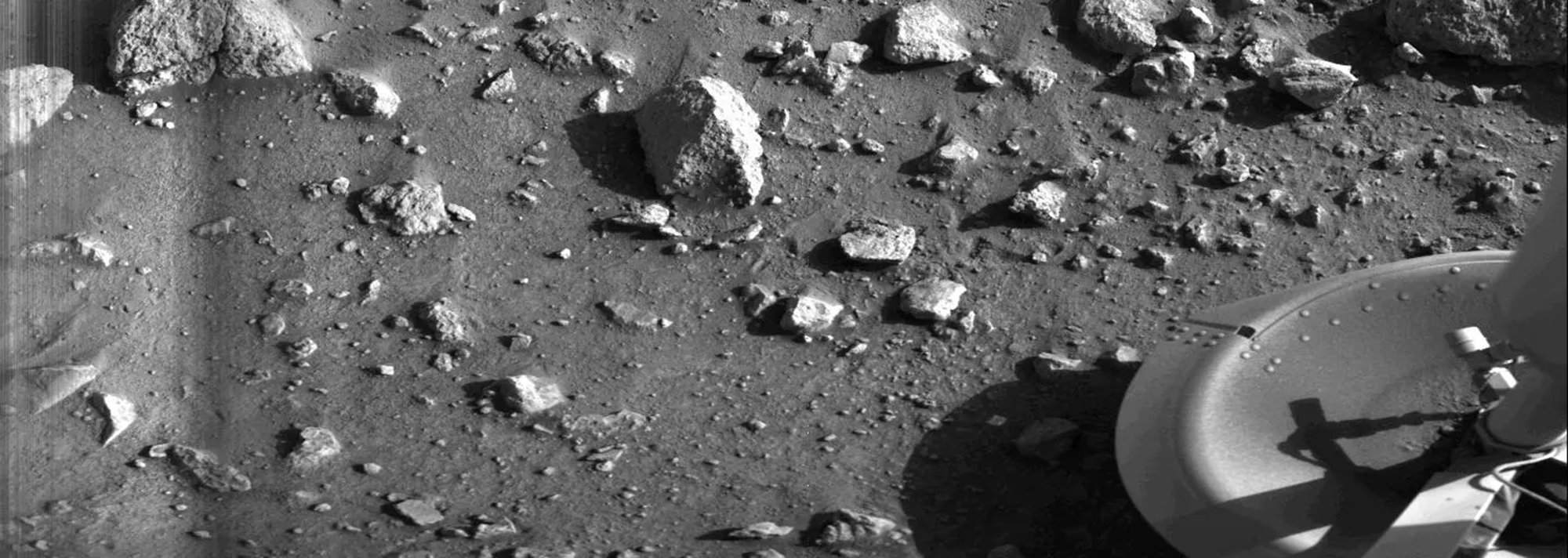 A grayscale image of a rocky surface with a metal leg on the right side of the image