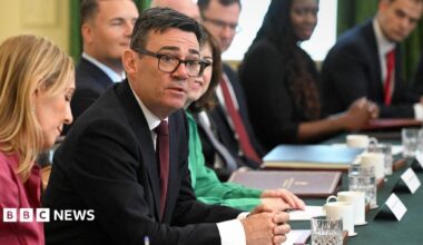 Burham looks up and towards the camera while sitting at a desk surrounded by cabinet members during a cabinet meeting in Downing Street on 21 July.