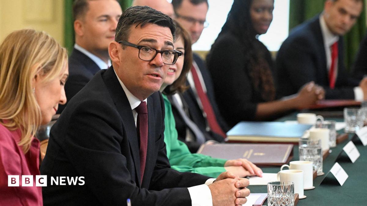 Burham looks up and towards the camera while sitting at a desk surrounded by cabinet members during a cabinet meeting in Downing Street on 21 July.