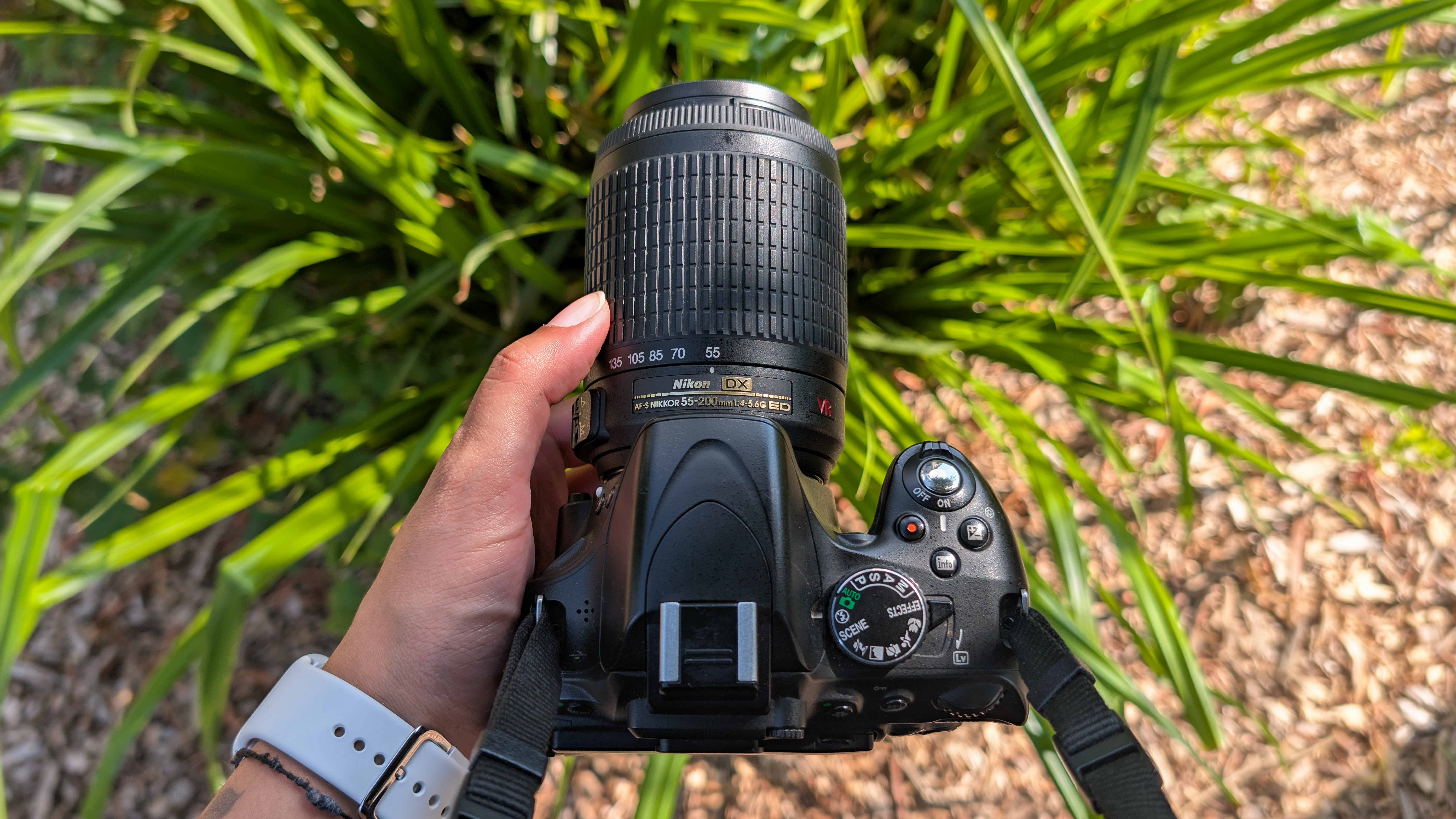 A person holding a Nikon D5100 DSLR camera