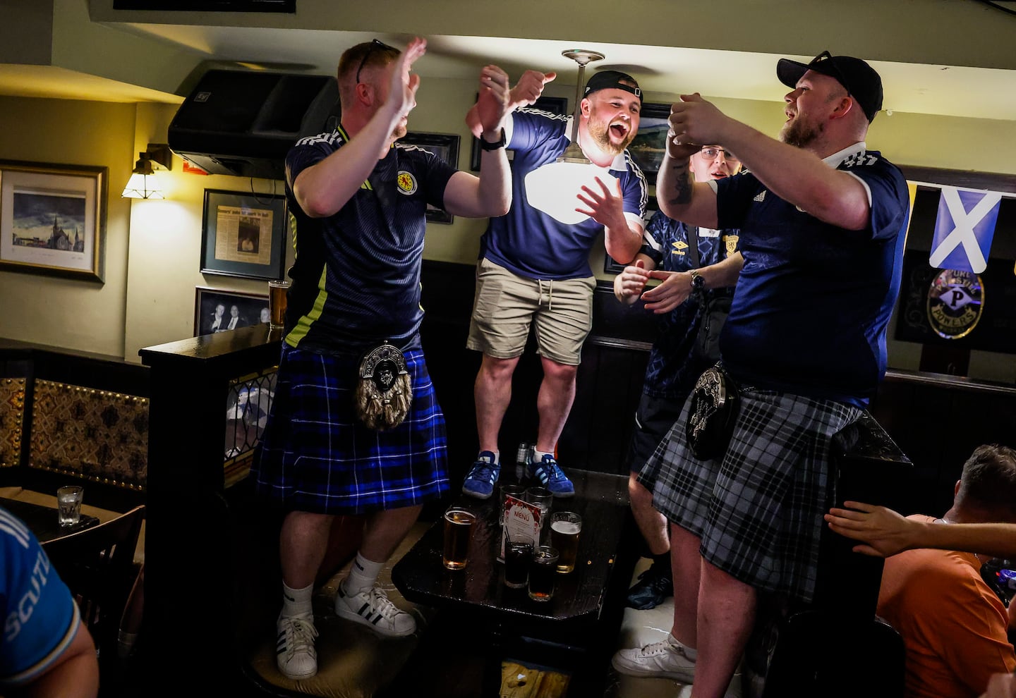 Scotland fan Greg McLeod, center, leads songs with other fans inside Hennessy's Bar.