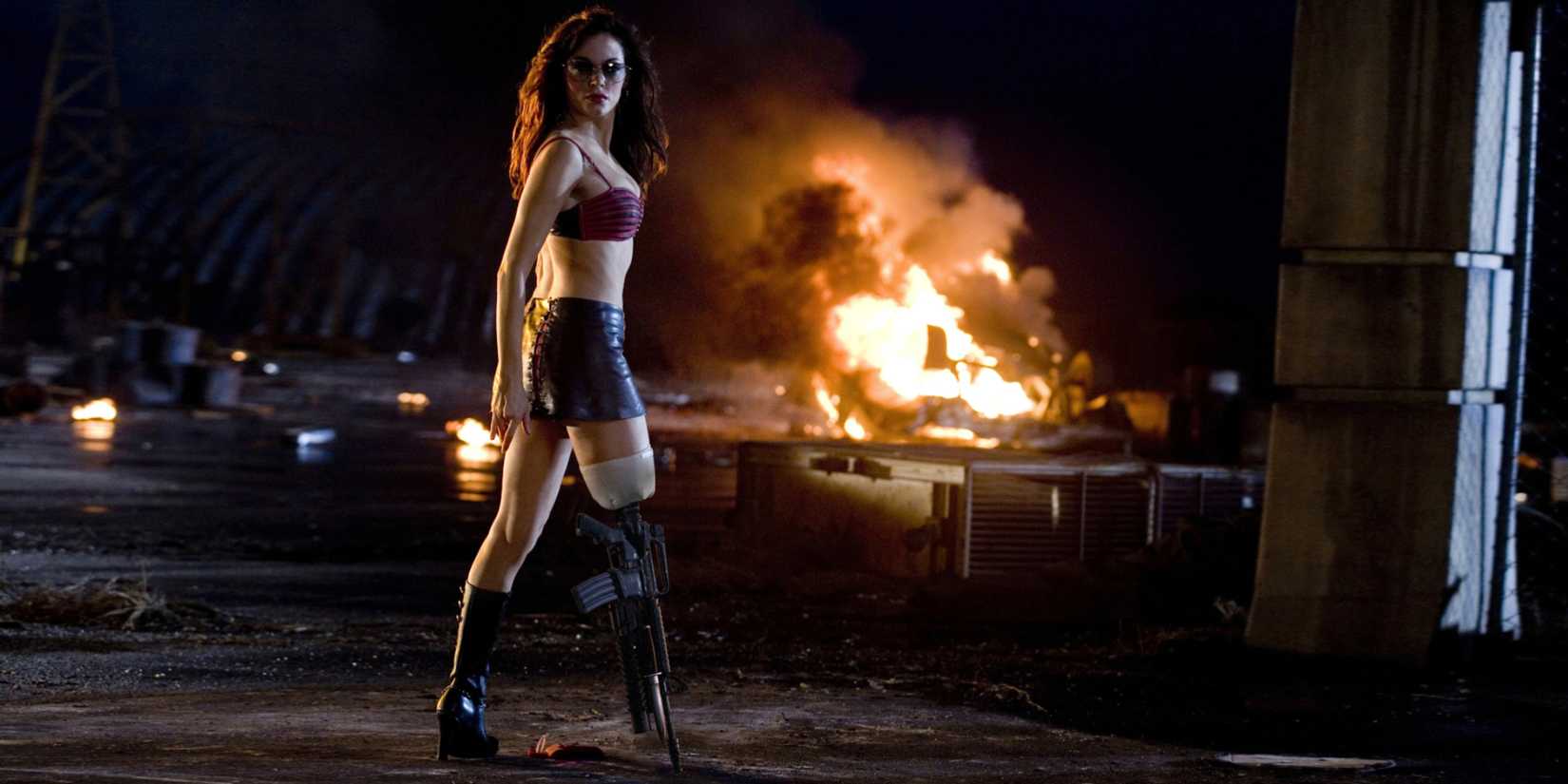 Rose McGowan standing with an explosion in the background in Grindhouse