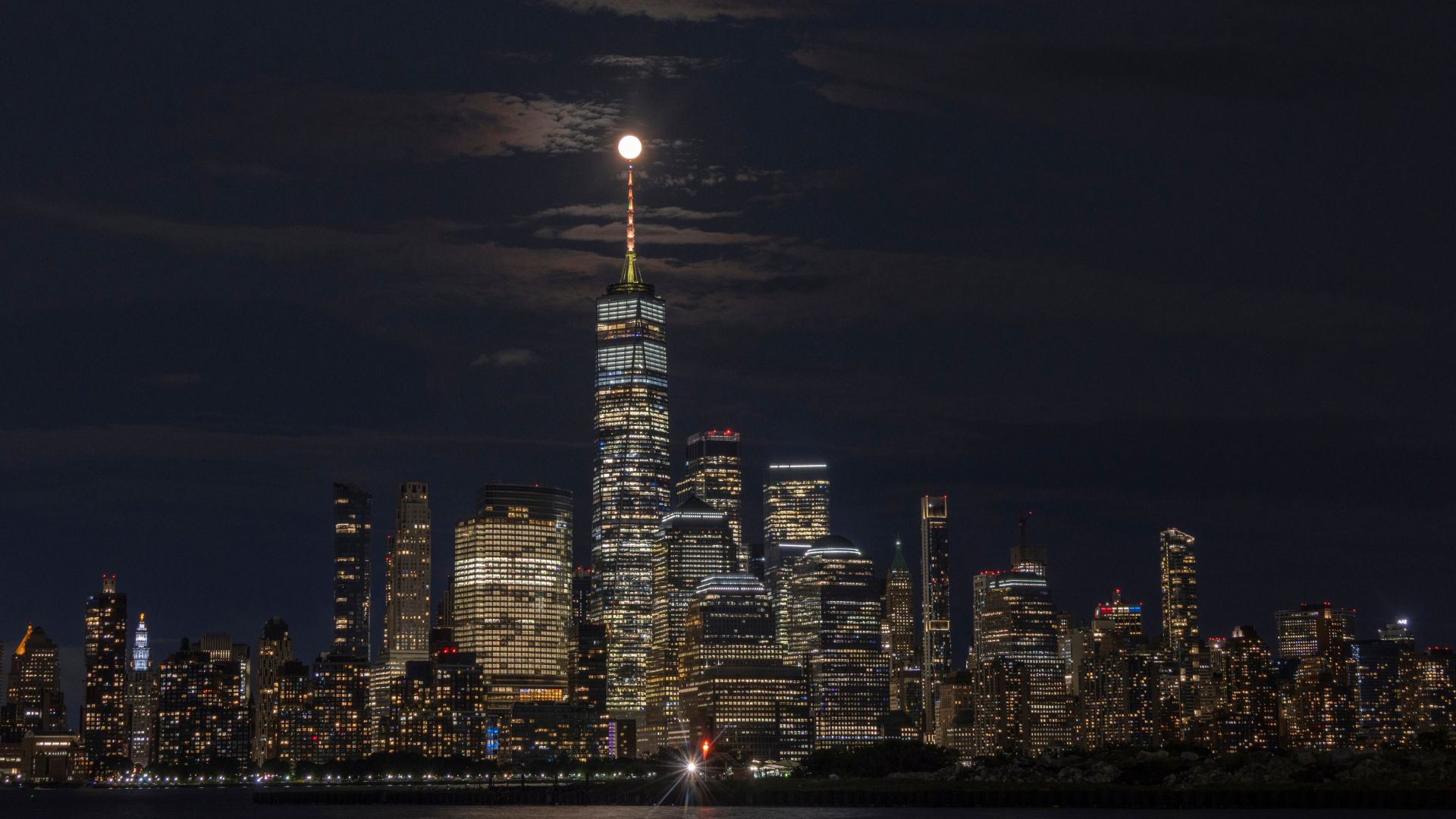 A full moon glows over the New York City skyline at night.